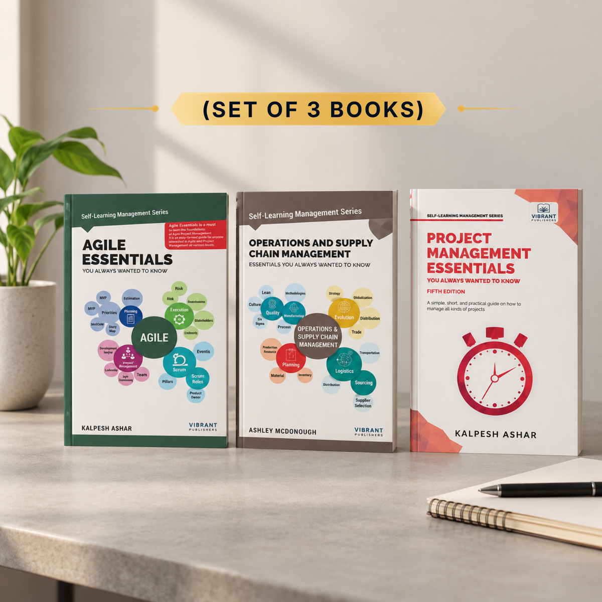 Three self-learning management books from the Vibrant Publications series are displayed on a light gray desk. The books are 'Agile Essentials', 'Operations and Supply Chain Management Essentials', and 'Project Management Essentials', shown as a set with a yellow banner above reading '(SET OF 3 BOOKS)'.
