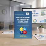 A book titled "Organizational Development Essentials" stands upright on a desk in front of a computer monitor showing charts and graphs. 